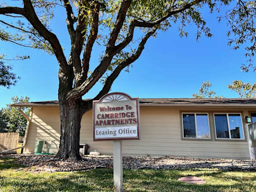 Leasing office sign at Cambridge Apartments that reads 'Welcome to Cambridge Leasing Office' in front of the building.