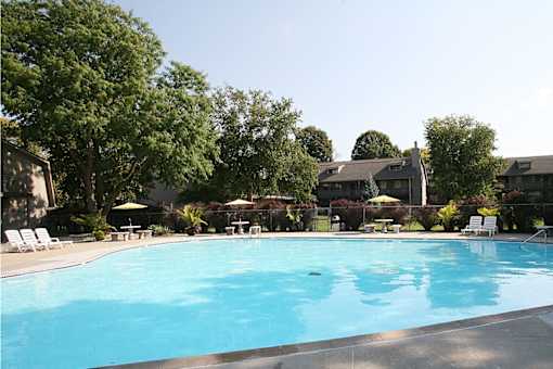 The swimming pool at Eden West Apartments, with lush greenery and trees surrounding the area.