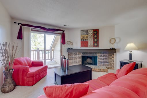 Living room in the one-bedroom model unit at Olde English Village, featuring a traditional stone-brick fireplace as a focal point.