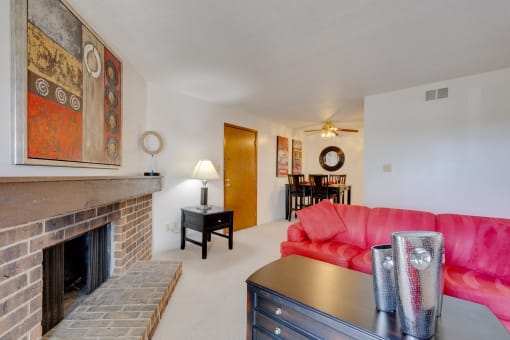 One-bedroom model unit living room at Olde English Village, showcasing a stone-brick fireplace and warm, inviting decor.