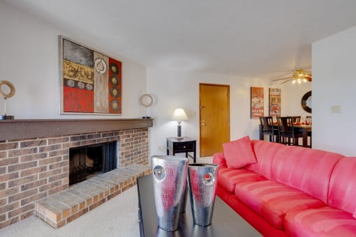 Living room in the one-bedroom model unit at Olde English Village, featuring a stone-brick fireplace and cozy seating.