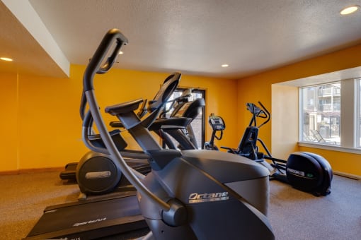 The fitness center at Olde English Village, offering exercise machines and free weights for residents.
