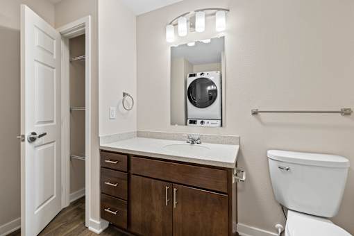 Bathroom with white toilet, sink with mirror, and white door at Olde English Village