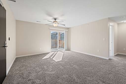 Spacious living room with ceiling fan and sliding door leading to a private balcony at Olde English Village