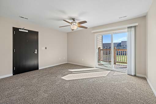 Living room with ceiling fan and front black door at Olde English Village
