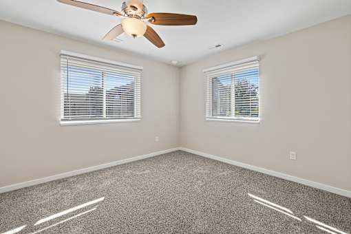 Room with ceiling fan and two windows at Olde English Village