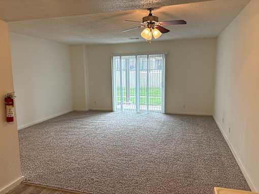 Vacant Apartment at Park 25 Apartments featuring carpeted flooring and a ceiling fan.