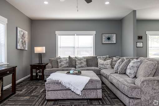 A living room with a grey couch and a white throw blanket on it.