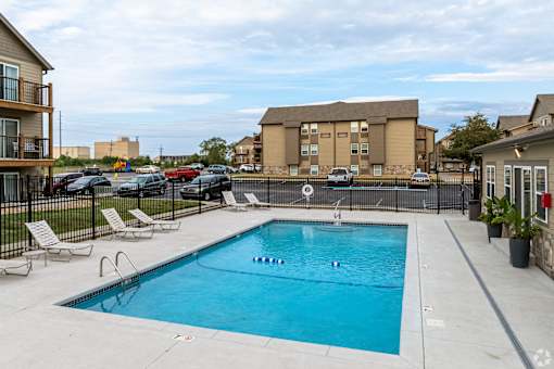 Swimming pool surrounded by a black fence with lounge chairs.