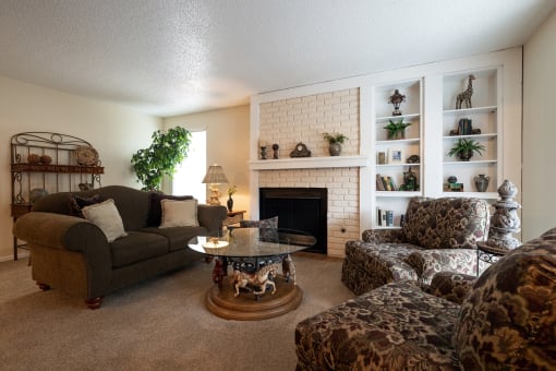 A cozy Tanglewood Model Unit-Living Room features comfortable couches and chairs around a welcoming fireplace.