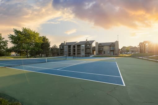 Tennis courts at The Lakes community, with apartment buildings in the background and a well-maintained playing surface.