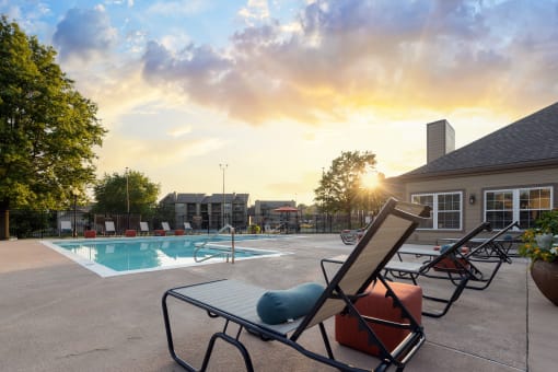 The pool area at The Lakes, complete with lounge chairs, a table, and comfortable seating around the pool.