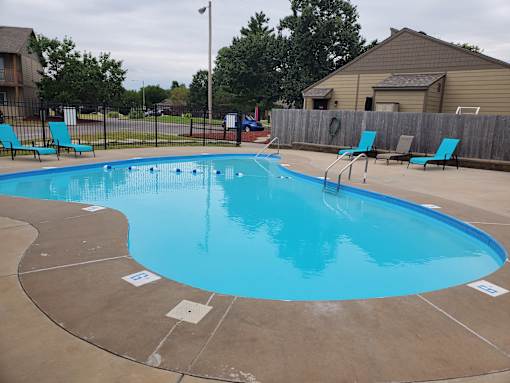Willow Creek Apartments - Pool area with lounge chairs and clear water.