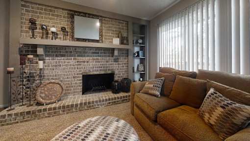 A cozy living room with a love seat, a fireplace, a floor clock, and a round coffee table, softly lit with warm lighting for a relaxing atmosphere.