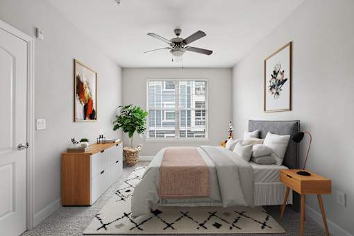 A bedroom with a bed, nightstand, and a ceiling fan.