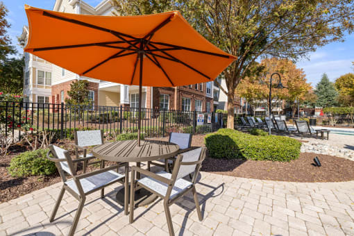 a patio with an orange umbrella and a table with chairs