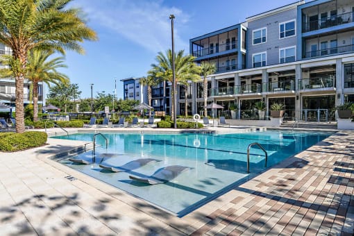 a large swimming pool in front of a building with palm trees