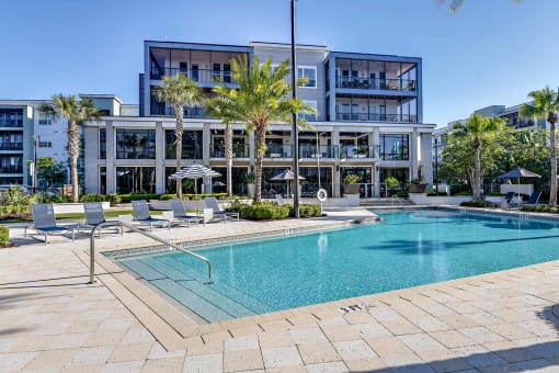 a swimming pool in front of a building with palm trees