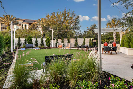 a backyard with a lawn and tables and chairs