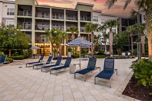 a group of lounge chairs on a patio in front of an apartment building