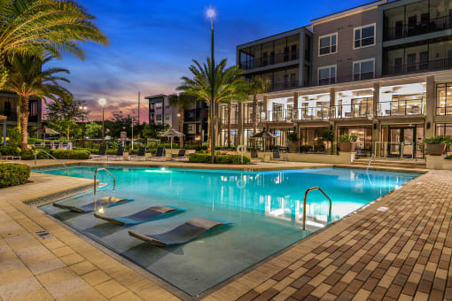 a swimming pool in front of a building with palm trees