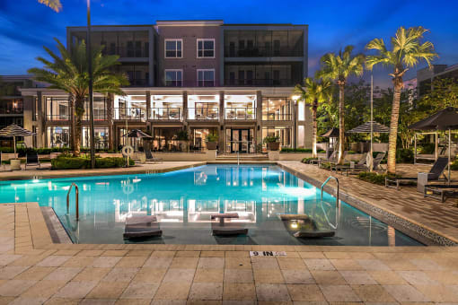 a large swimming pool in front of a hotel at night