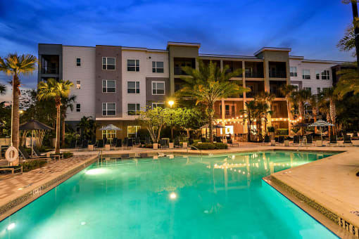 a large swimming pool in front of an apartment building at night