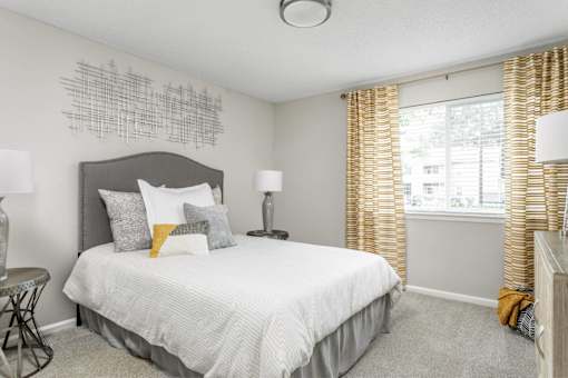 A bedroom with a bed, two lamps, and a chair.