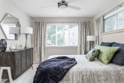 A bedroom with a bed, a dresser, and a window with curtains.