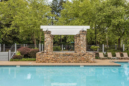 A pool with a stone pillar and a white roof.