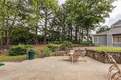 A backyard with a stone wall and a table set for four.
