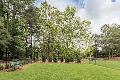 A park with a green bench and trees.