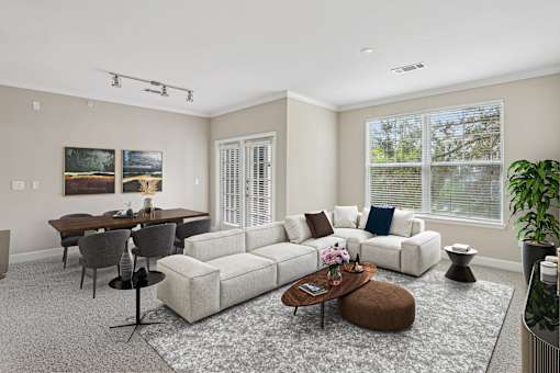 A living room with a white couch, a coffee table, and a dining table.