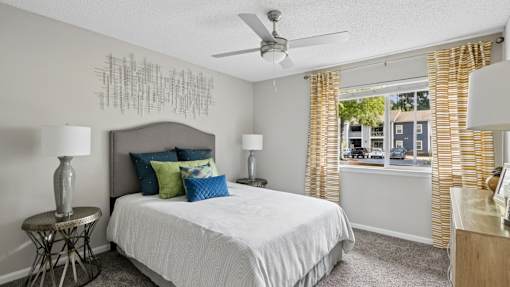 A bedroom with a bed, two lamps, and a ceiling fan.