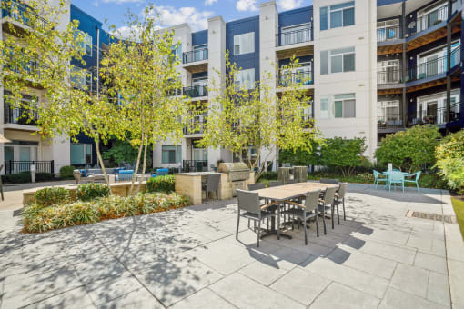a patio with a table and chairs in front of an apartment building