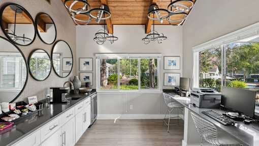 A kitchen with a desk and chairs in front of a window.