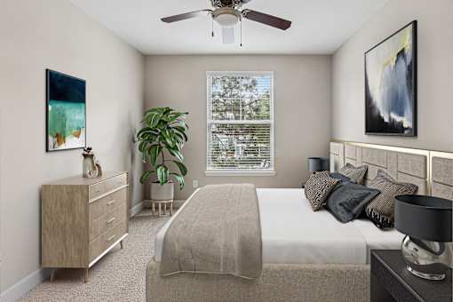 A bedroom with a bed, nightstand, and a painting on the wall.