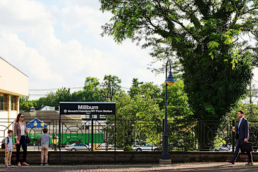 A sign that says Millburn stands in front of a tree.
