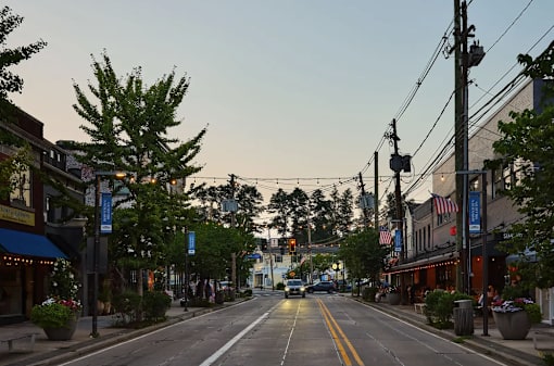 A street view of a small town with a car driving down the road.