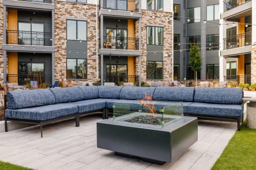 an outdoor patio with couches and a fire pit in front of an apartment building at Stonehill at West Orange, New Jersey