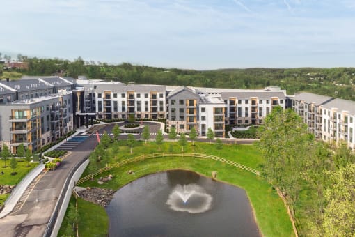 an aerial view of a building with a fountain in the middle of a pond at Stonehill at West Orange, West Orange, New Jersey