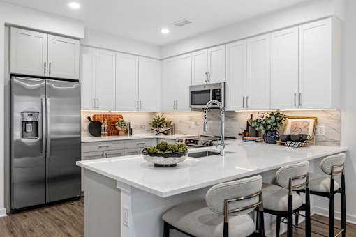 Modern kitchen with white cabinetry and island seating at The Piermont Apartments, Hillsdale, 07642