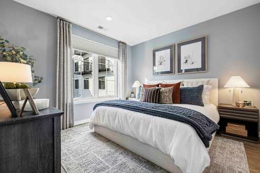Bedroom with white bedding and large window at The Piermont Apartments, Hillsdale, New Jersey