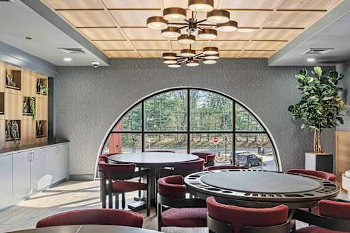 Community game room with card tables and arched window at The Piermont Apartments, New Jersey, 07642