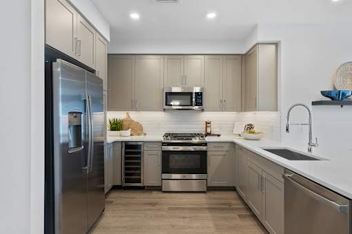 A modern kitchen with a stainless steel refrigerator and a microwave above the stove at The Reserve at Pearl River Apartments, Pearl River, NY