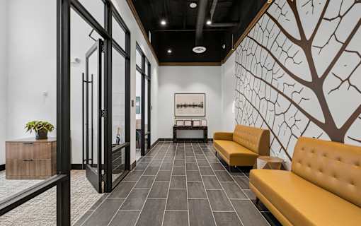 A hallway with a yellow sofa and a tree mural on the wall.