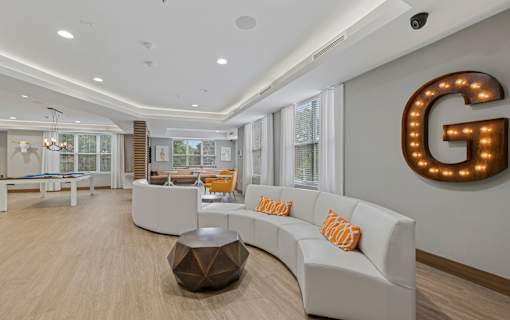 A modern living room with a white sofa and a large letter G on the wall.
