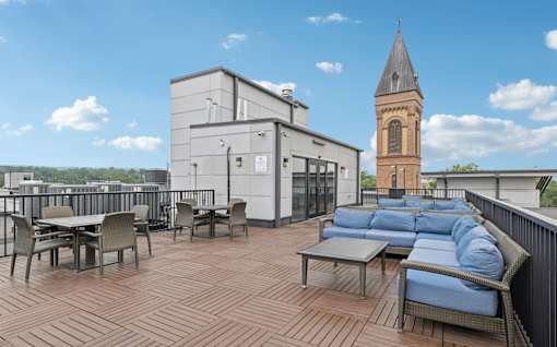 A patio with a table and chairs overlooking a church tower.