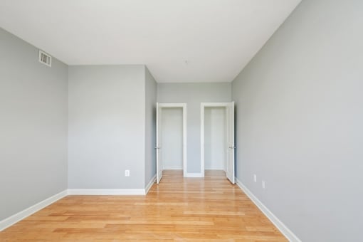 a bedroom with grey walls and a hardwood floor