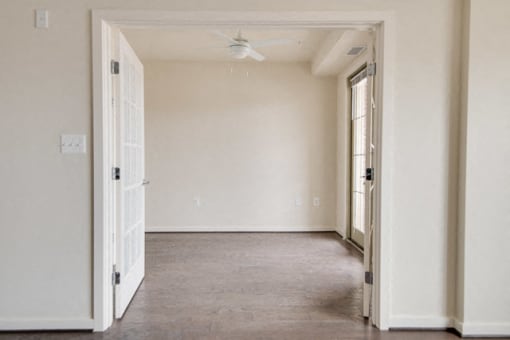 an empty room with a door open and a ceiling fan